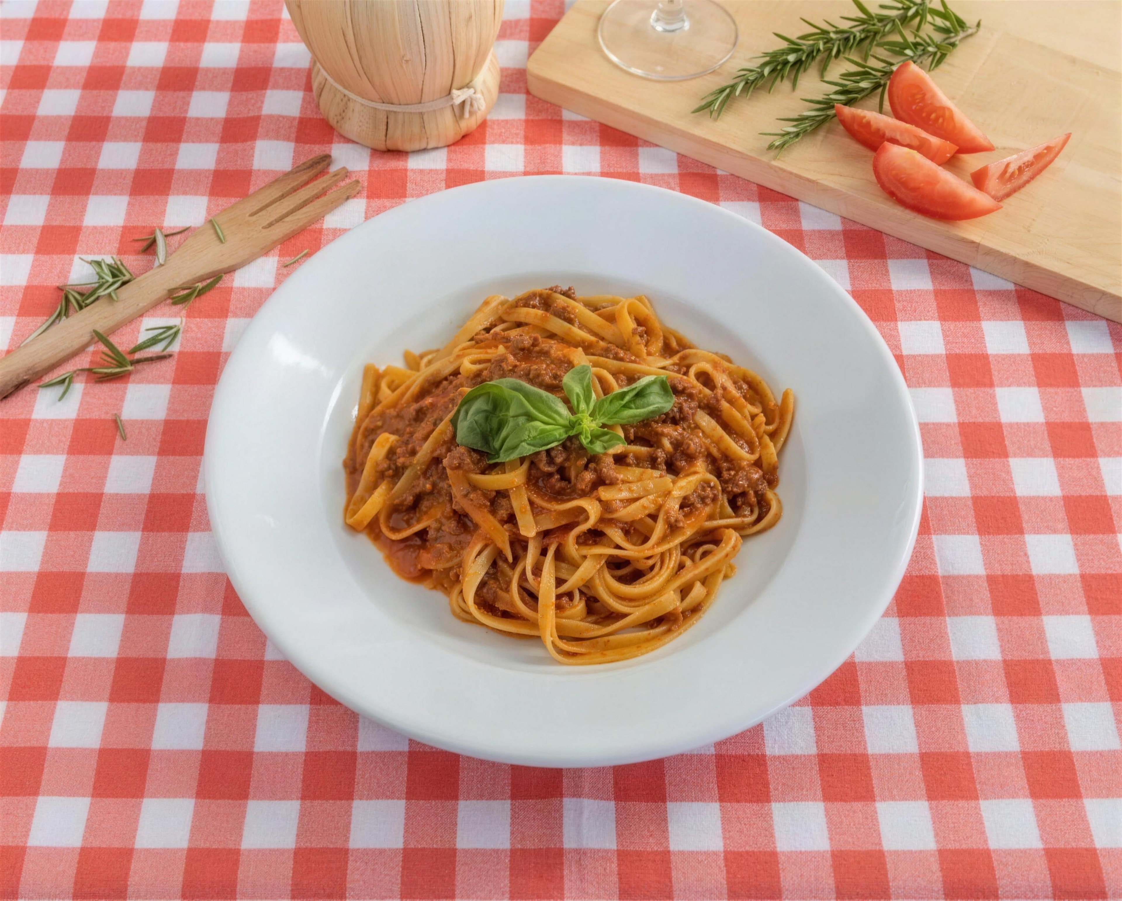 Fettuccine Bolognese topped with a basil leaf in a white bowl